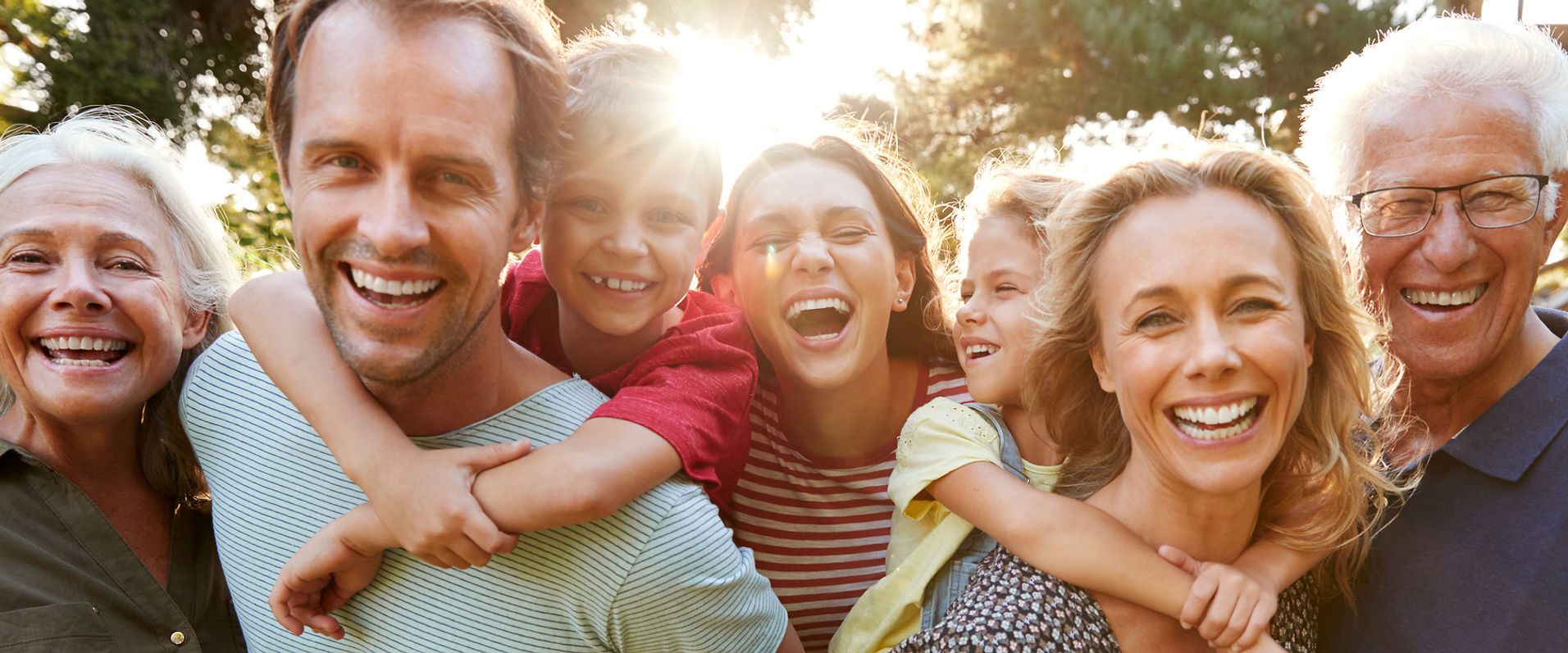 Família reunida, de várias gerações, sorrindo ao ar livre